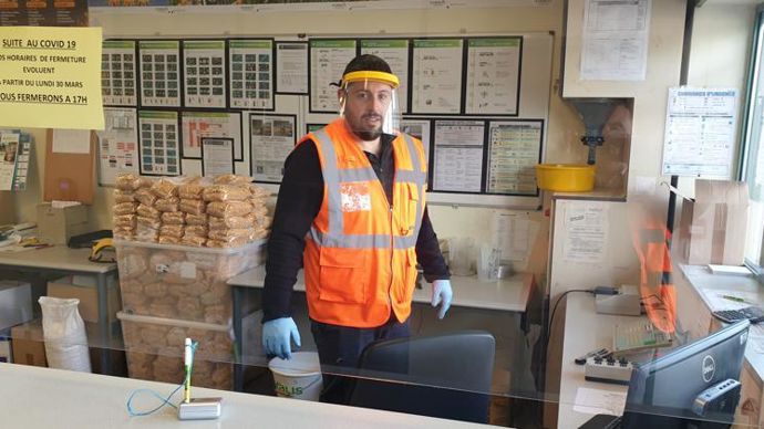 Vincent Arretteig, conseiller vendeur au silo Euralis d’Oloron-Sainte-Marie, est équipé de gants et d’une visière de motoculture, et protégé par une vitre en plexiglas qui longe le comptoir. © C. POEYDOMENGE/EURALIS